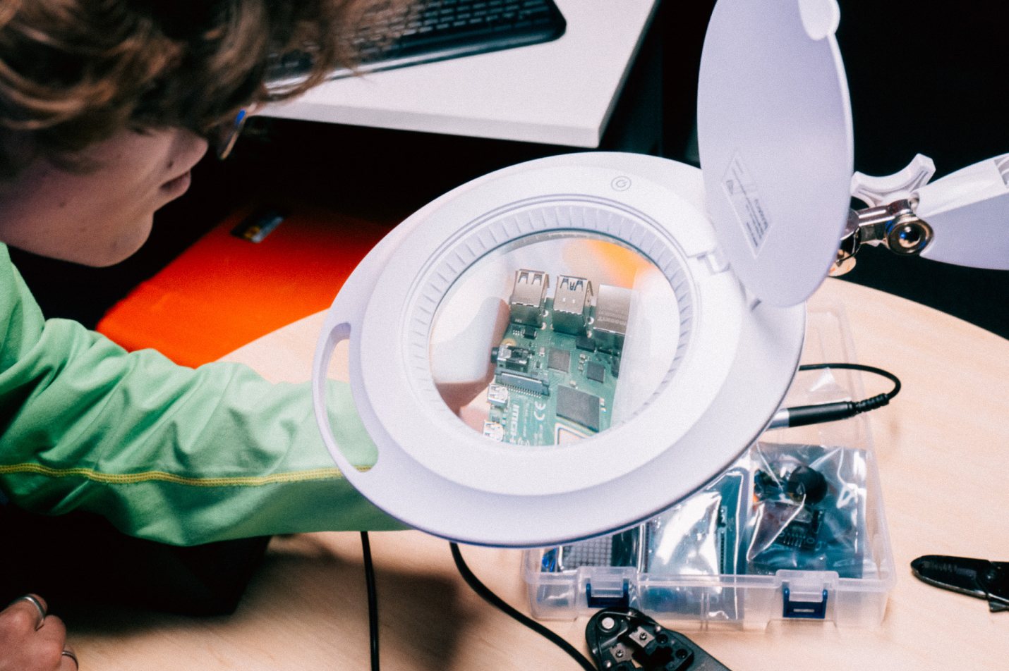 A student at a work desk inspecting computer hardware | Computer Science