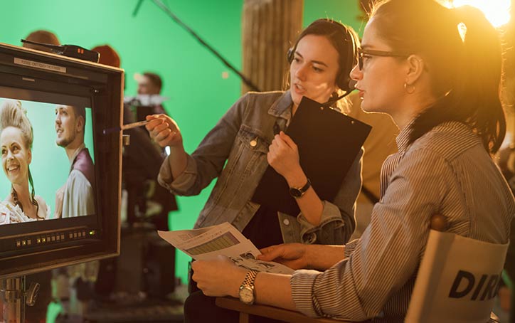 Two people review monitor. Green screen and sound foley in background.