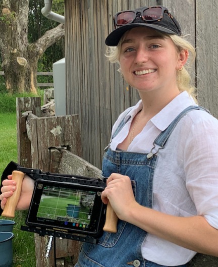 Photo of Mia Charleson standing outside, holding a film camera - SAE Bachelor of Film (Production) alumni