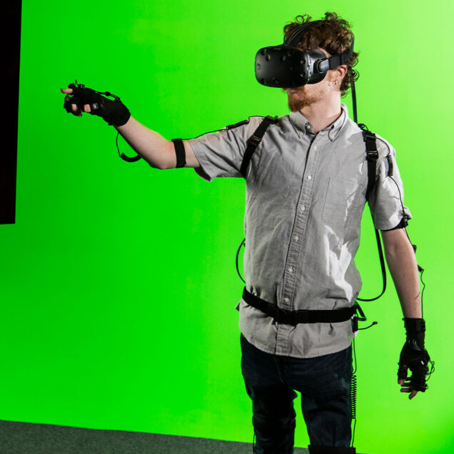 Man stands wearing VR headset and tracking gloves