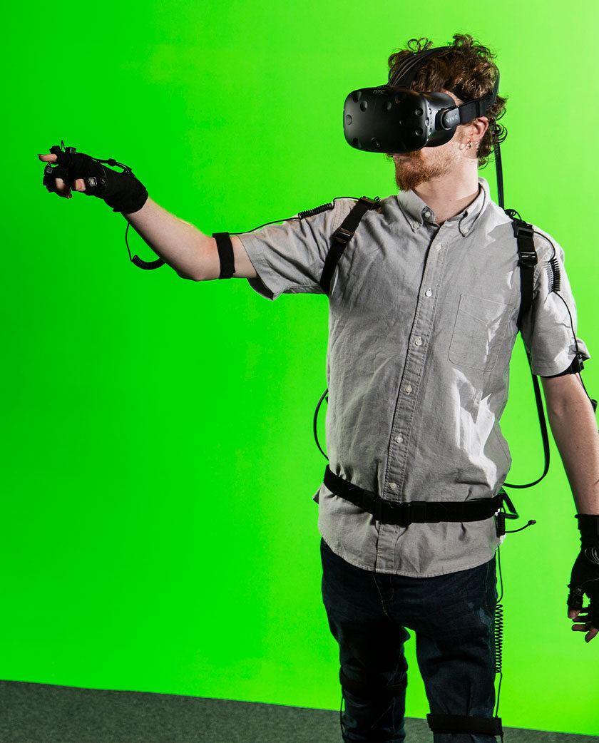 Man stands wearing VR headset and tracking gloves