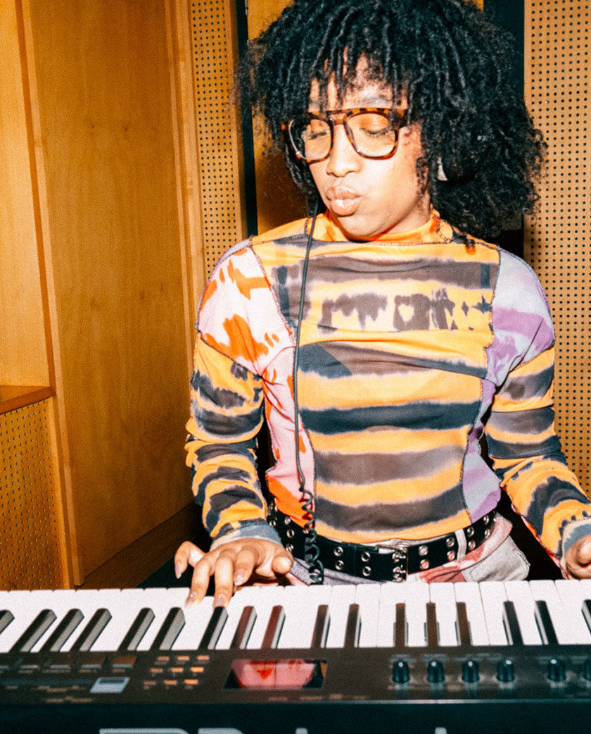 Woman wearing glasses standing above and looking down at keyboard. She appears to be playing the keyboard - her fingers are on the keys.