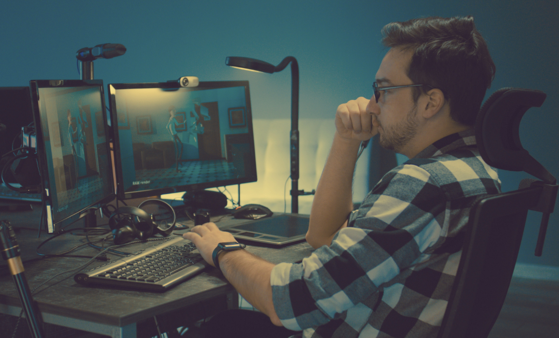 man in plaid sitting behind two computer screens working on an animation | time management tips