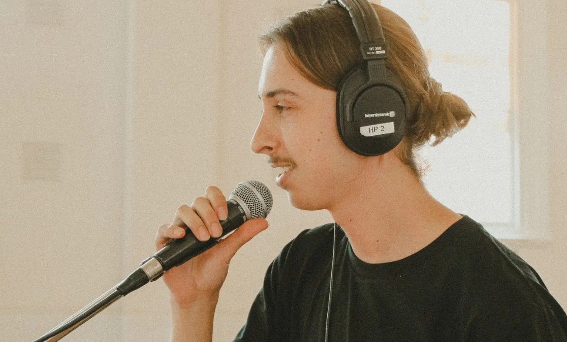 young man with headphone on speaks into a microphone