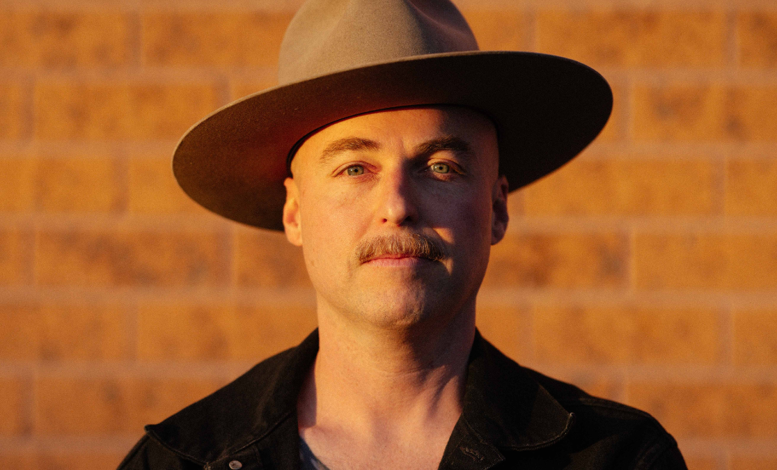 man in hat in front of brick wall in sunset light