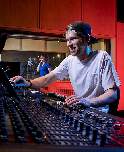 SAE Audio Engineering alumni Ben Rompotis operating audio engineering equipment in a studio with red lighting - desktop image
