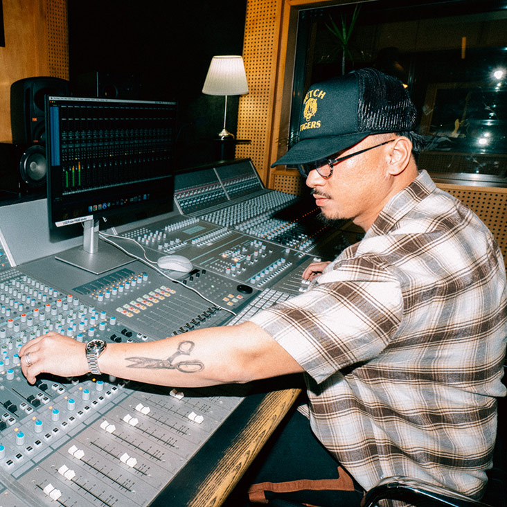 A male SAE Audio student wearing a cap and glasses, operating audio hardware in a professional studio