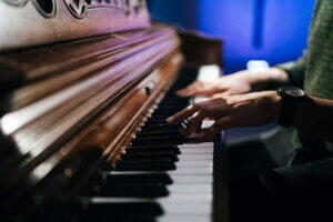Student sits at piano and hands are placed on and playing piano