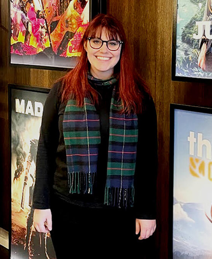 SAE Games alumni Elise Marchouba standing in an office in front of various posters of video games - mobile image