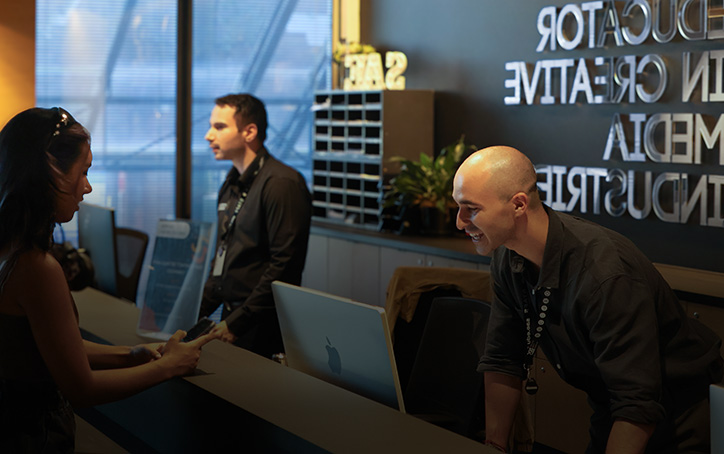 Two SAE University College student advisors assisting students at a reception desk - image for mobile