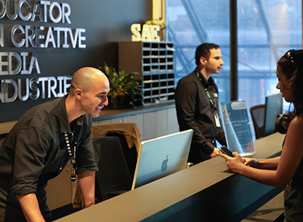 Two SAE University College student advisors assisting students at a reception desk - tile image 420x316