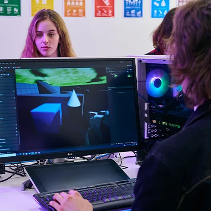 Students sit at monitors reviewing editing software on screen used in creative industries.