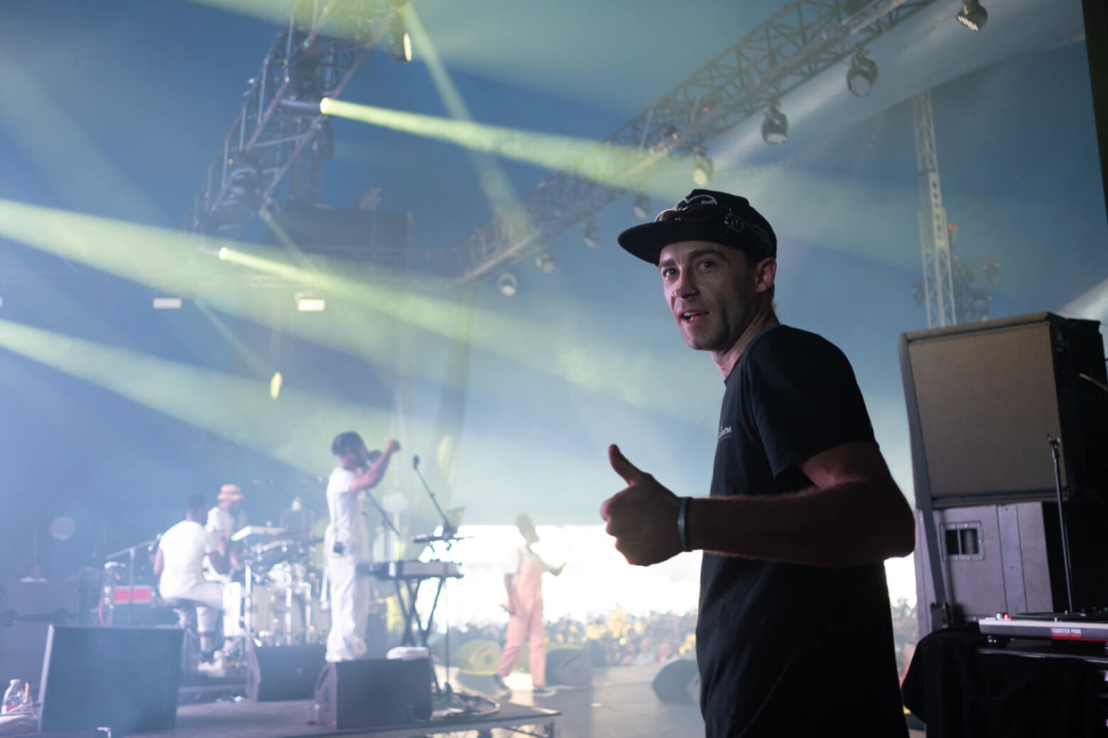 SAE student stands holding a thumbs up backstage as an audio crew - behind the scenes