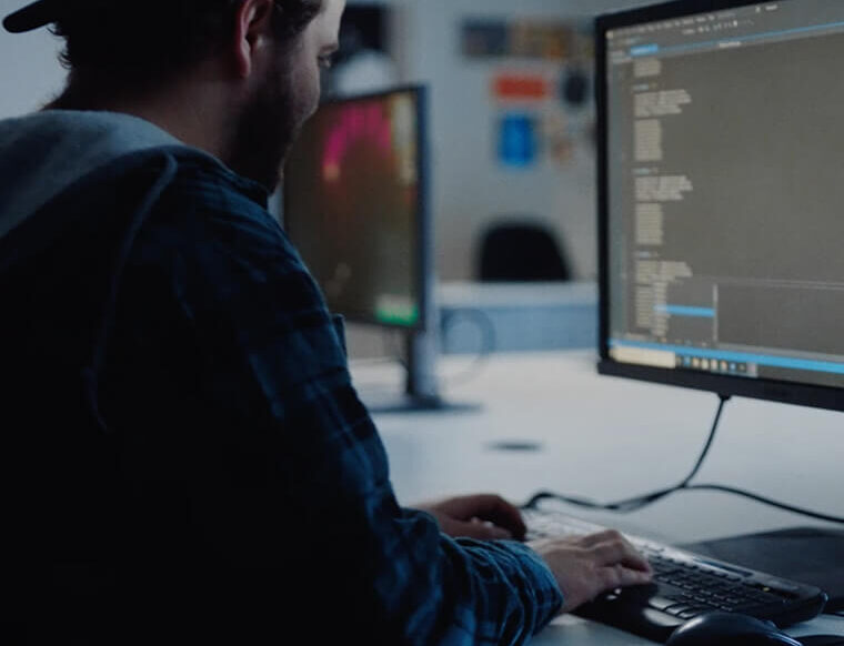 Person with a backwards cap working on a computer full of code language