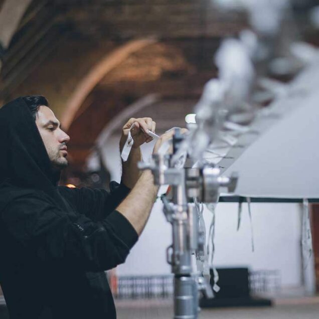 Male adjusting film / lighting screen on set