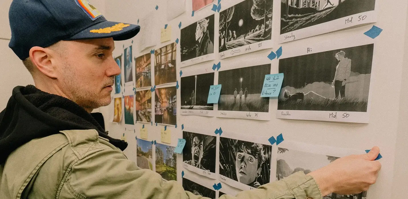 SAE Master of Creative Industries alumni Mark Gambino taping images from a storyboard on to a white wall in a studio (1430x700)